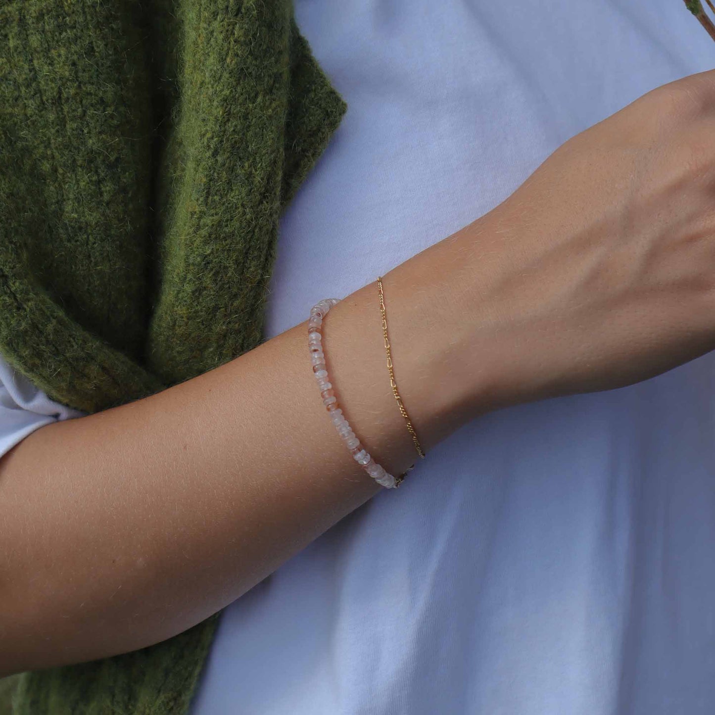 Close-up of a person's arm wearing two bracelets on a light blue background