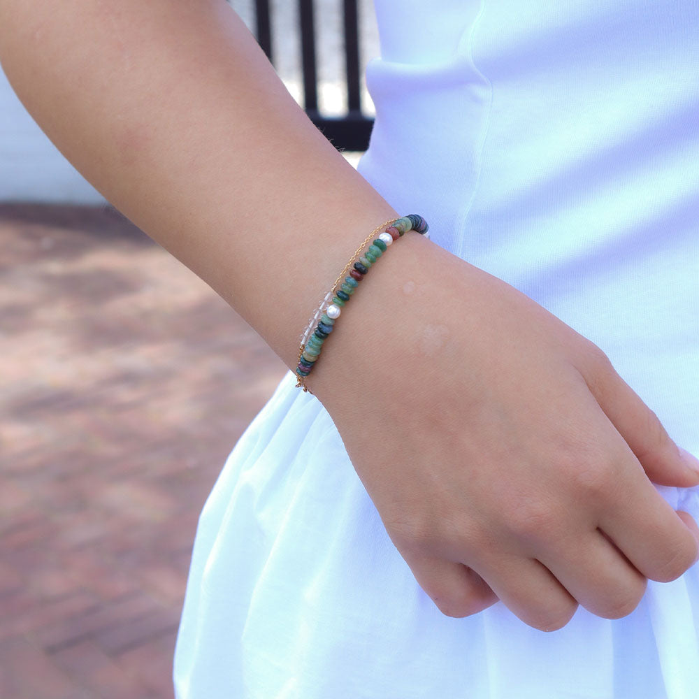 Close-up of a woman's wrist wearing a beaded bracelet with a blurred background