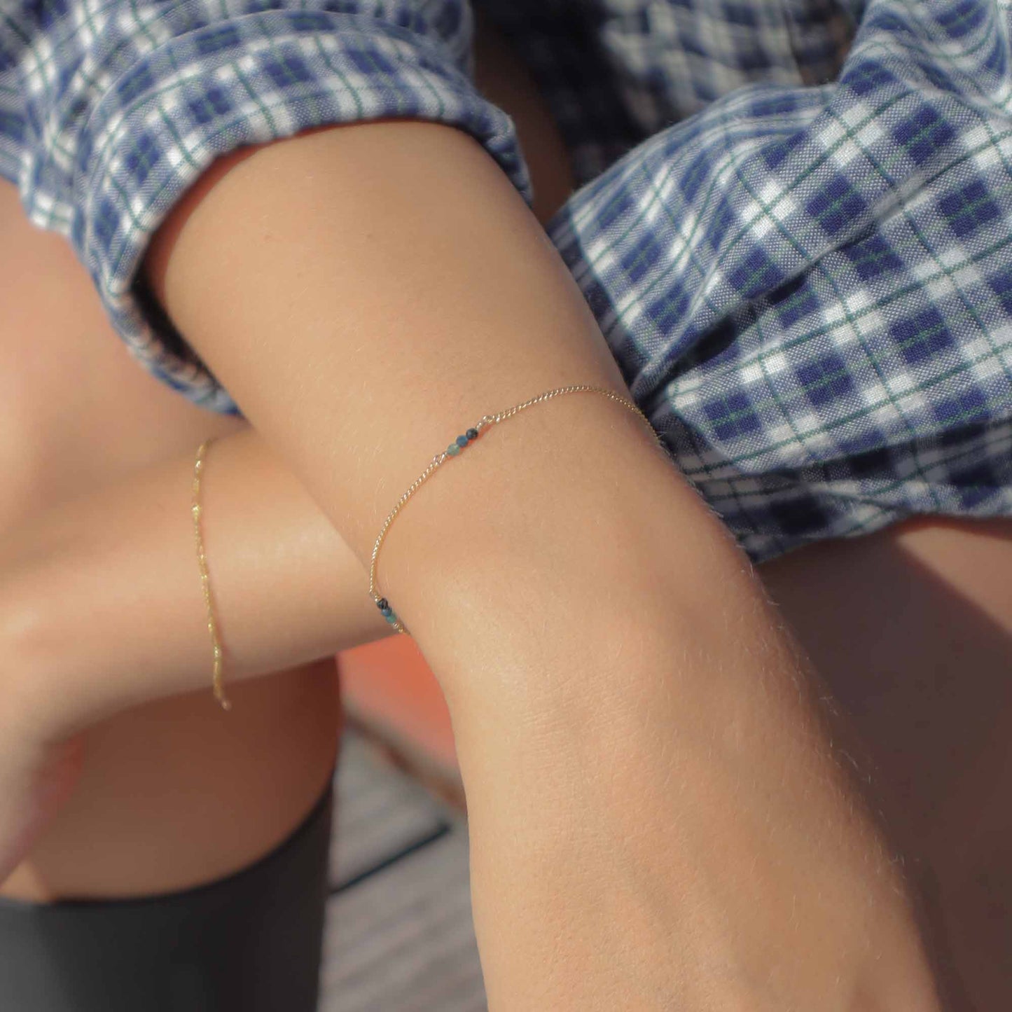 Close-up of a person wearing a gold bracelet with small beads on their wrist.