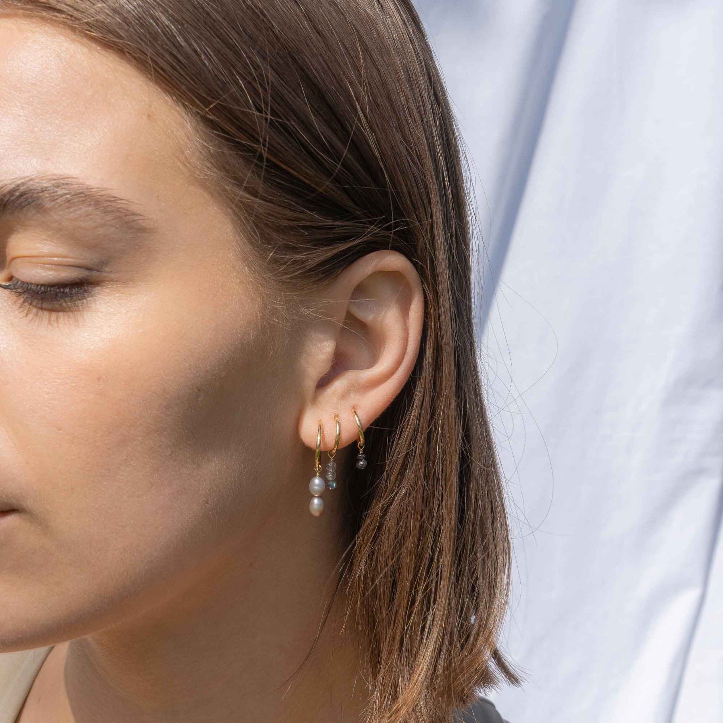 Close-up of a woman's ear wearing pearl earrings with a blurred background