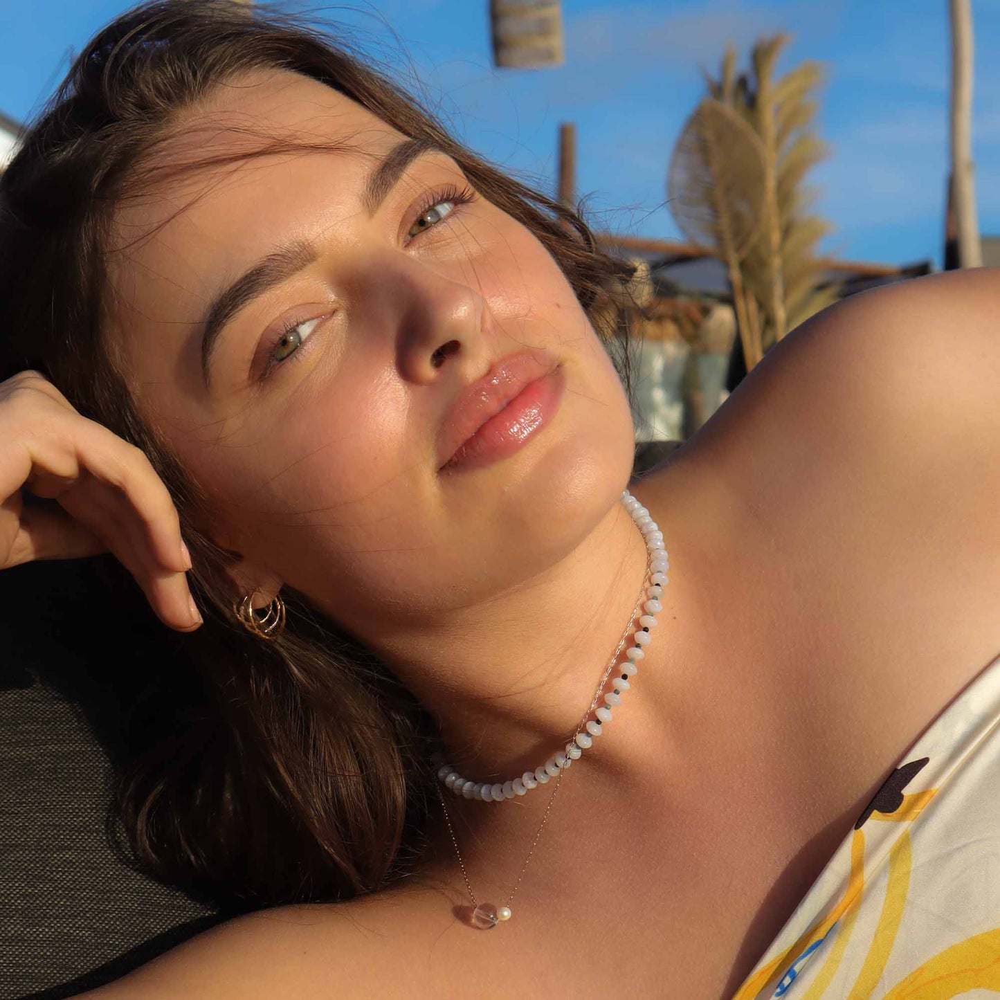 Woman wearing a necklace with a blurred outdoor background