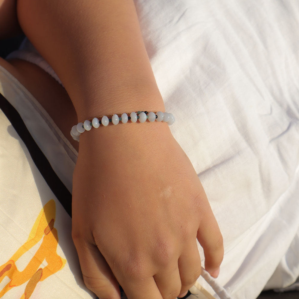 Hand wearing a beaded bracelet on a white background