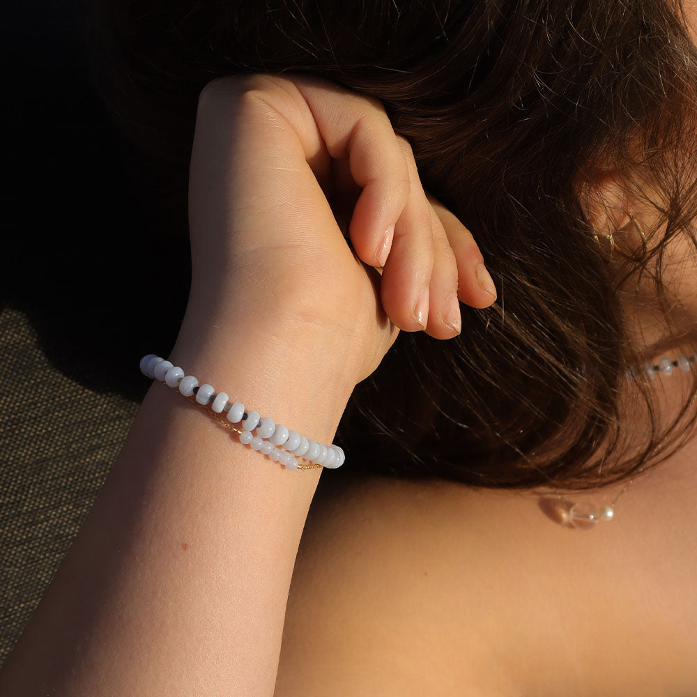 Person wearing a beaded bracelet with sunlight casting shadows