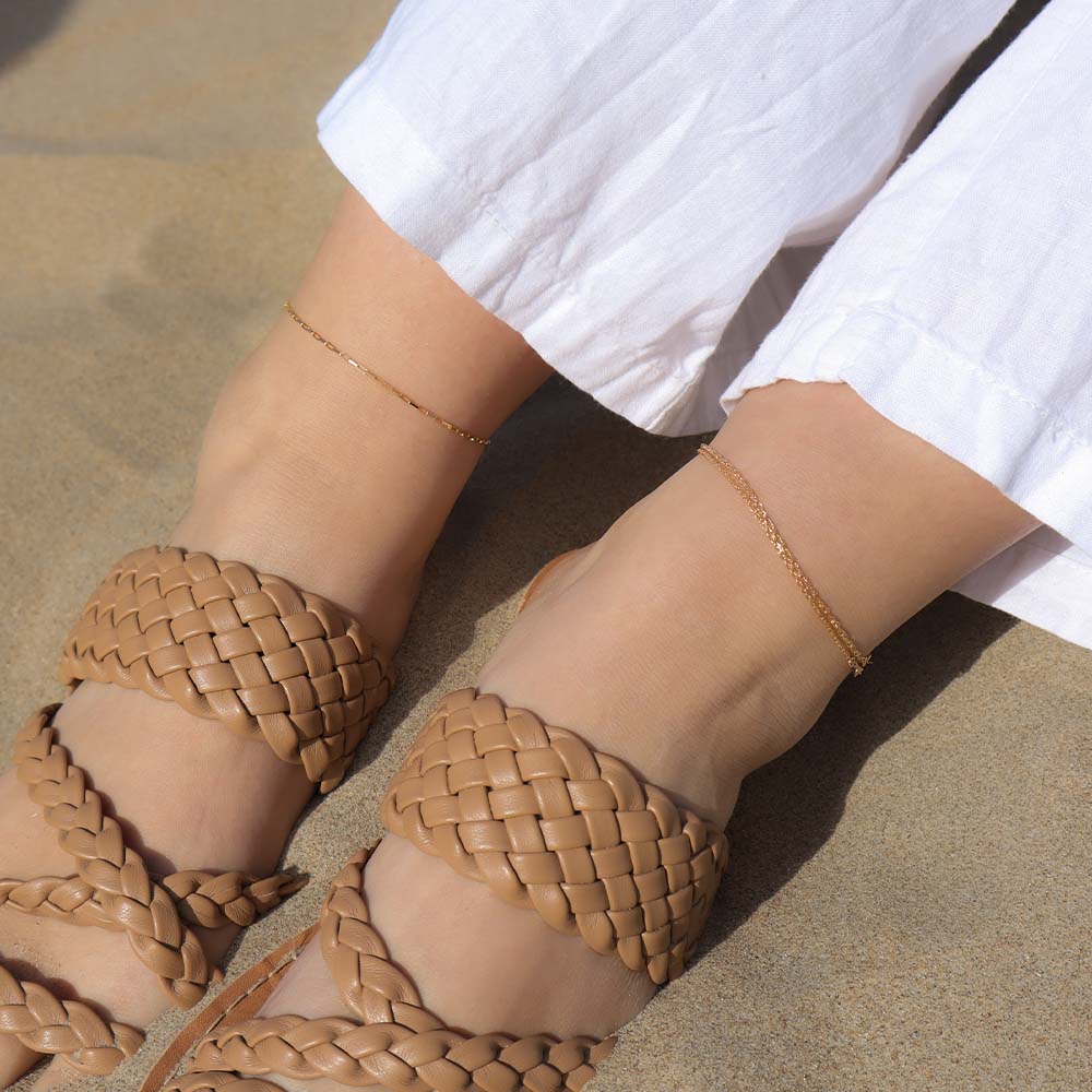 Brown woven sandals worn on a sandy surface