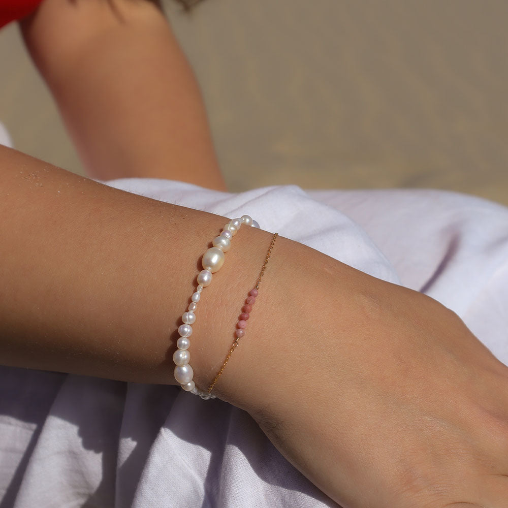 Close-up of a wrist wearing two pearl bracelets on a blurred background