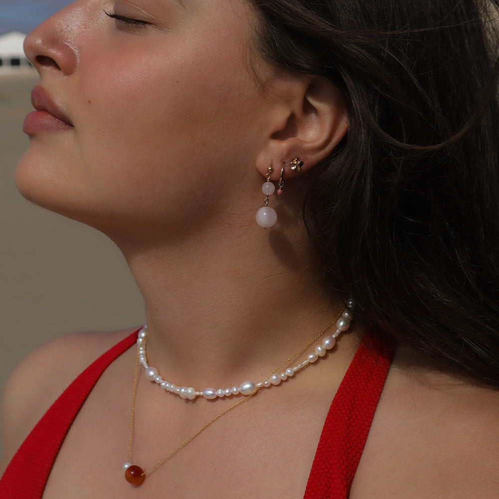 Close-up of a woman wearing a pearl necklace and earrings with a blurred background