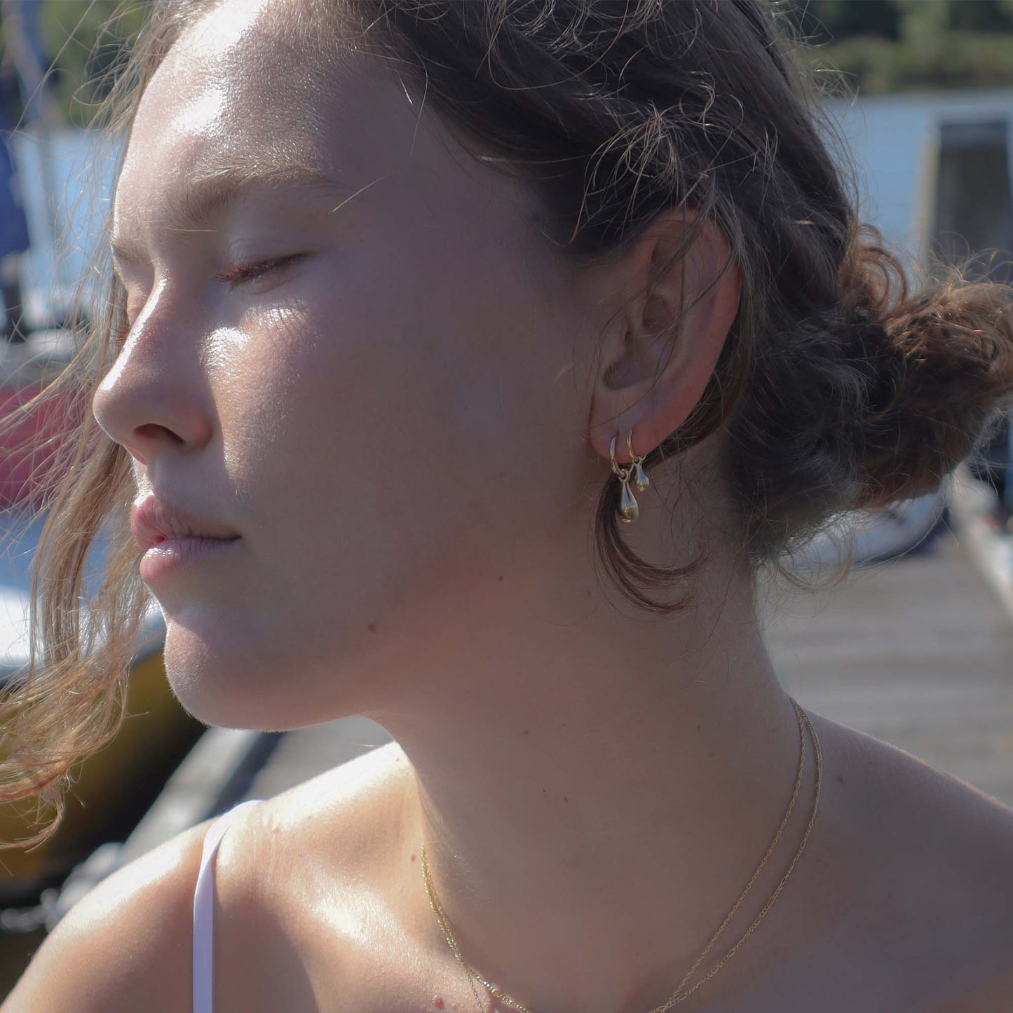 Close-up of a woman with braided hair and earrings outdoors