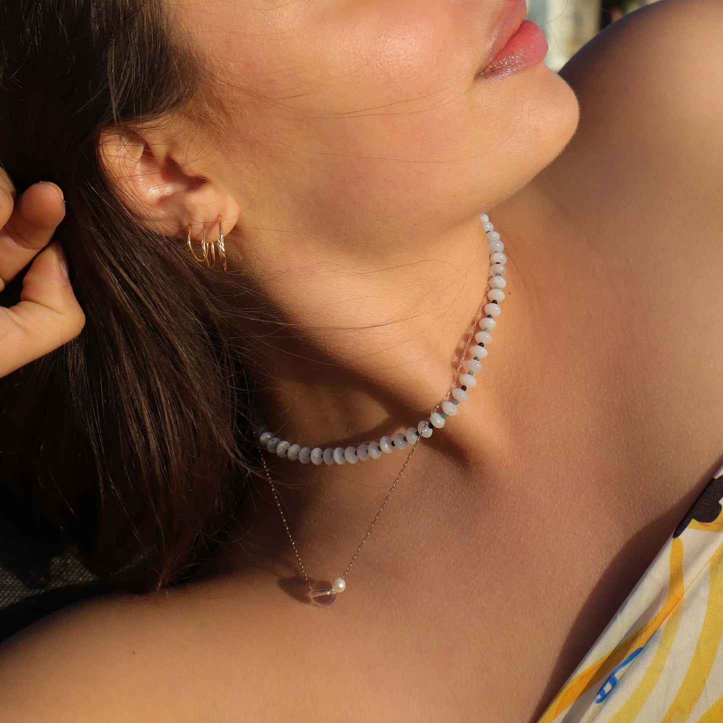 Close-up of a woman wearing a necklace and hoop earrings.