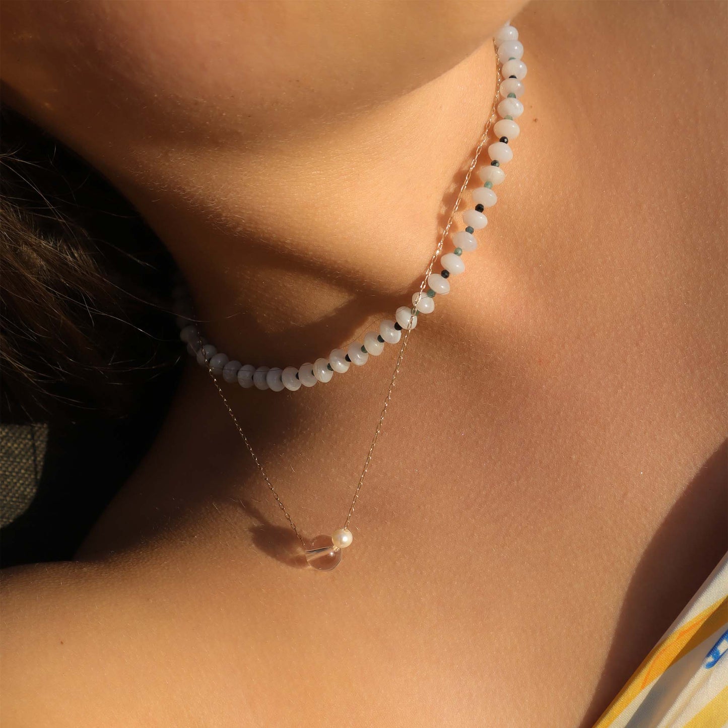Close-up of a person wearing a delicate necklace with small beads.