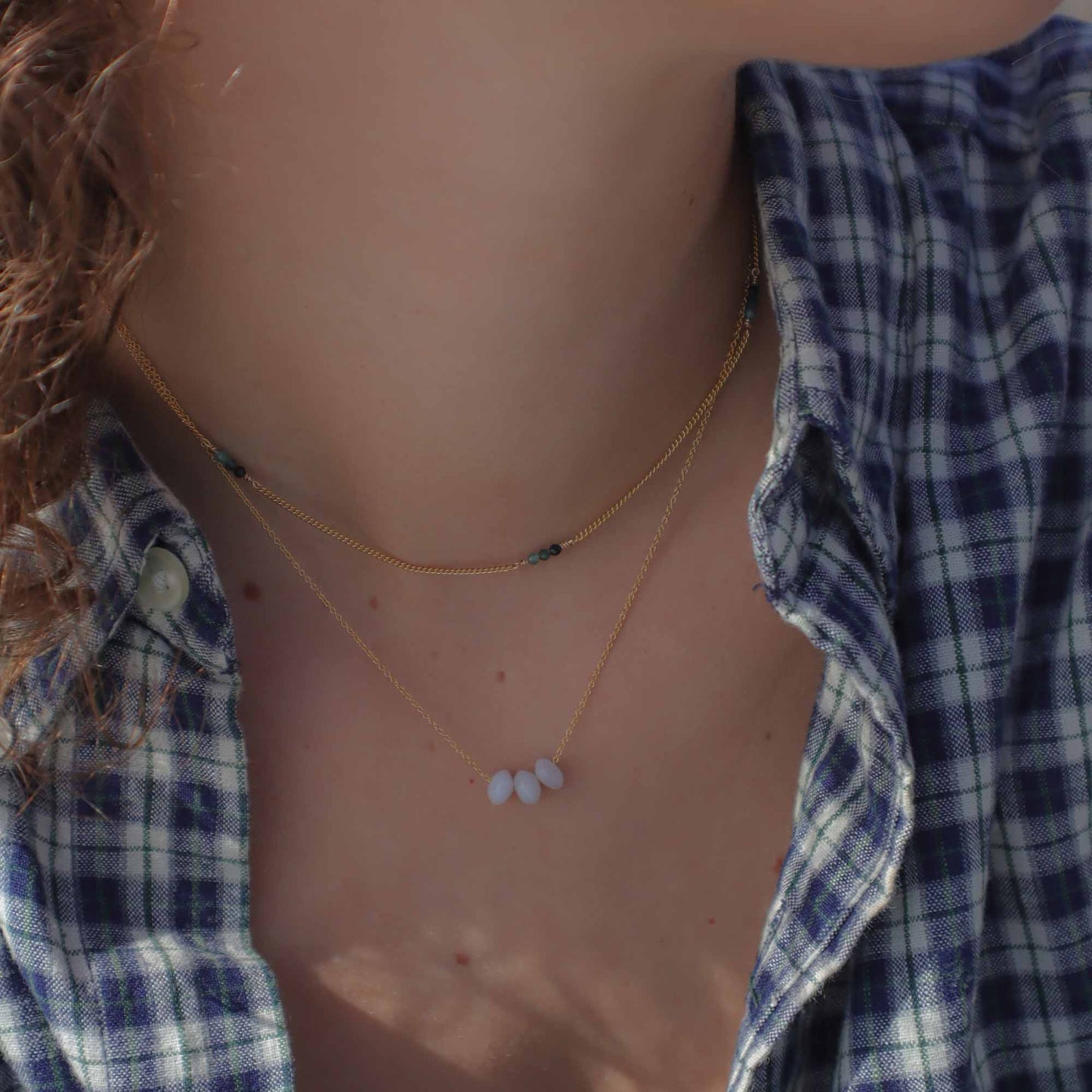 Necklace with small beads worn by a person in a plaid shirt