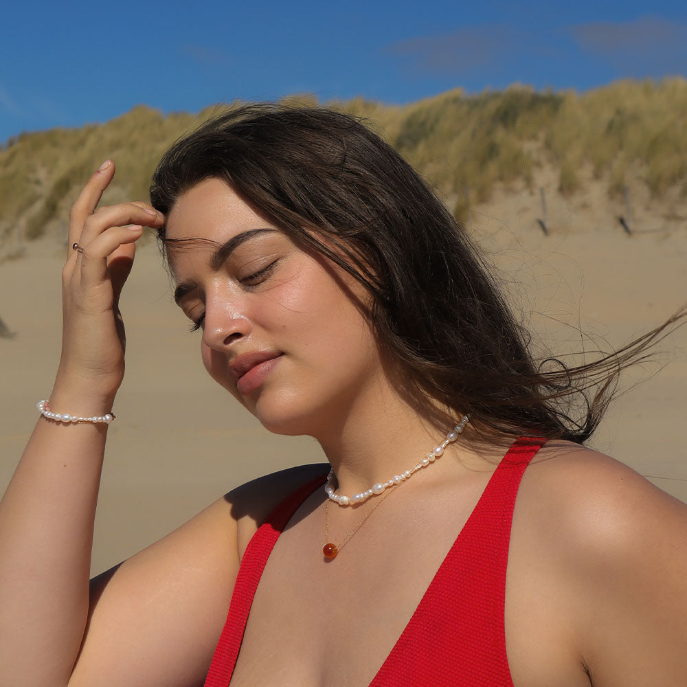 Woman in a red dress on a sandy beach with sand dunes in the background