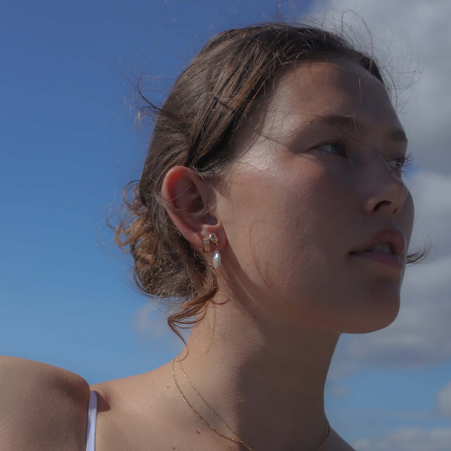 Woman with a pearl earring against a blue sky