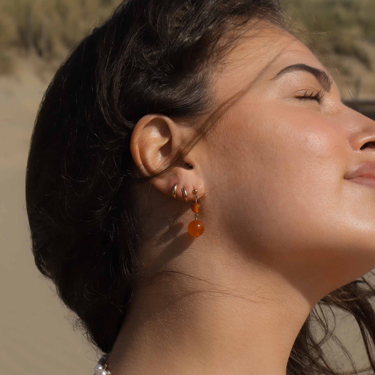 Close-up of a woman wearing earrings with a blurred natural background