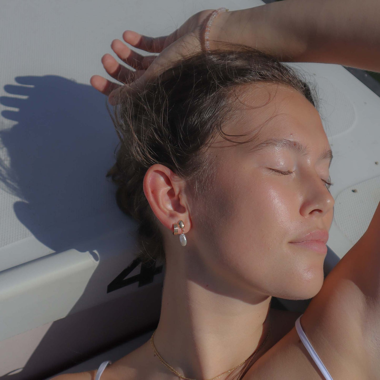 Woman with closed eyes, sunbathing on a white surface