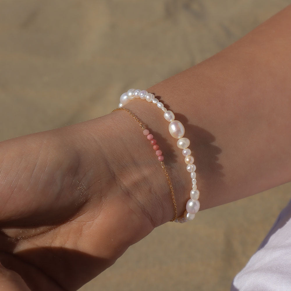 Close-up of a wrist wearing a pearl bracelet with a blurred background
