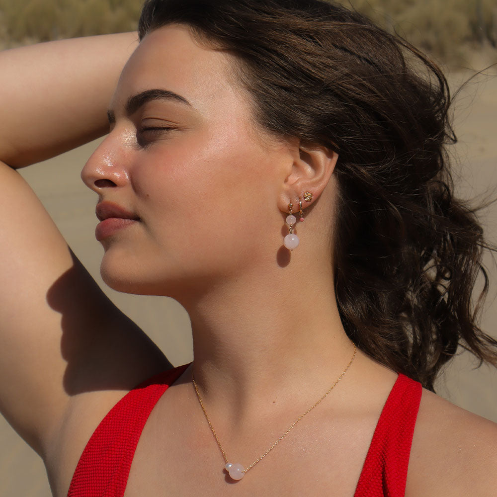 Woman with a red top and earrings against a natural background