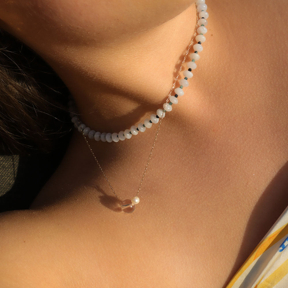 Close-up of a person wearing a delicate necklace with a small pendant.