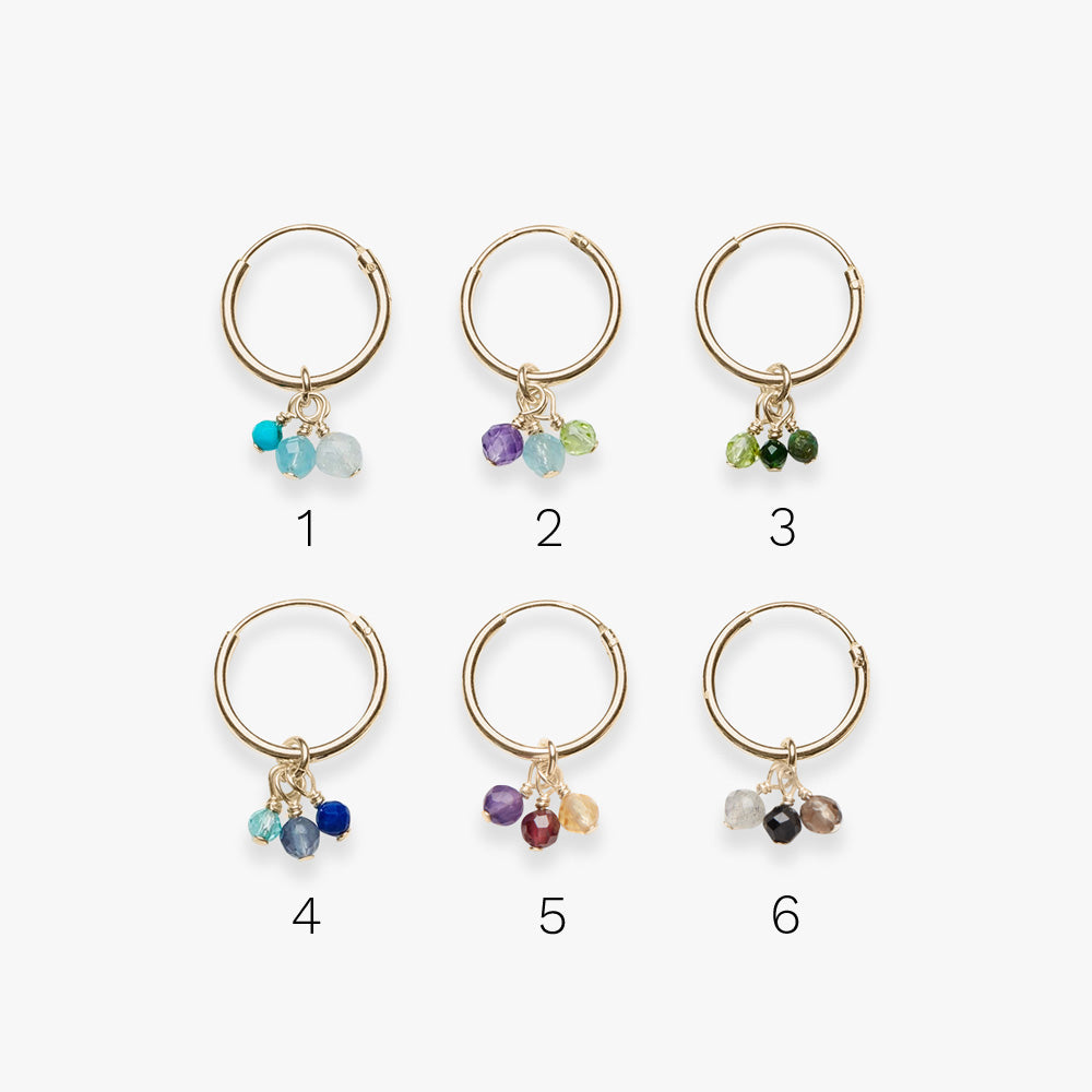 Set of six gold hoop earrings with colorful beads on a white background