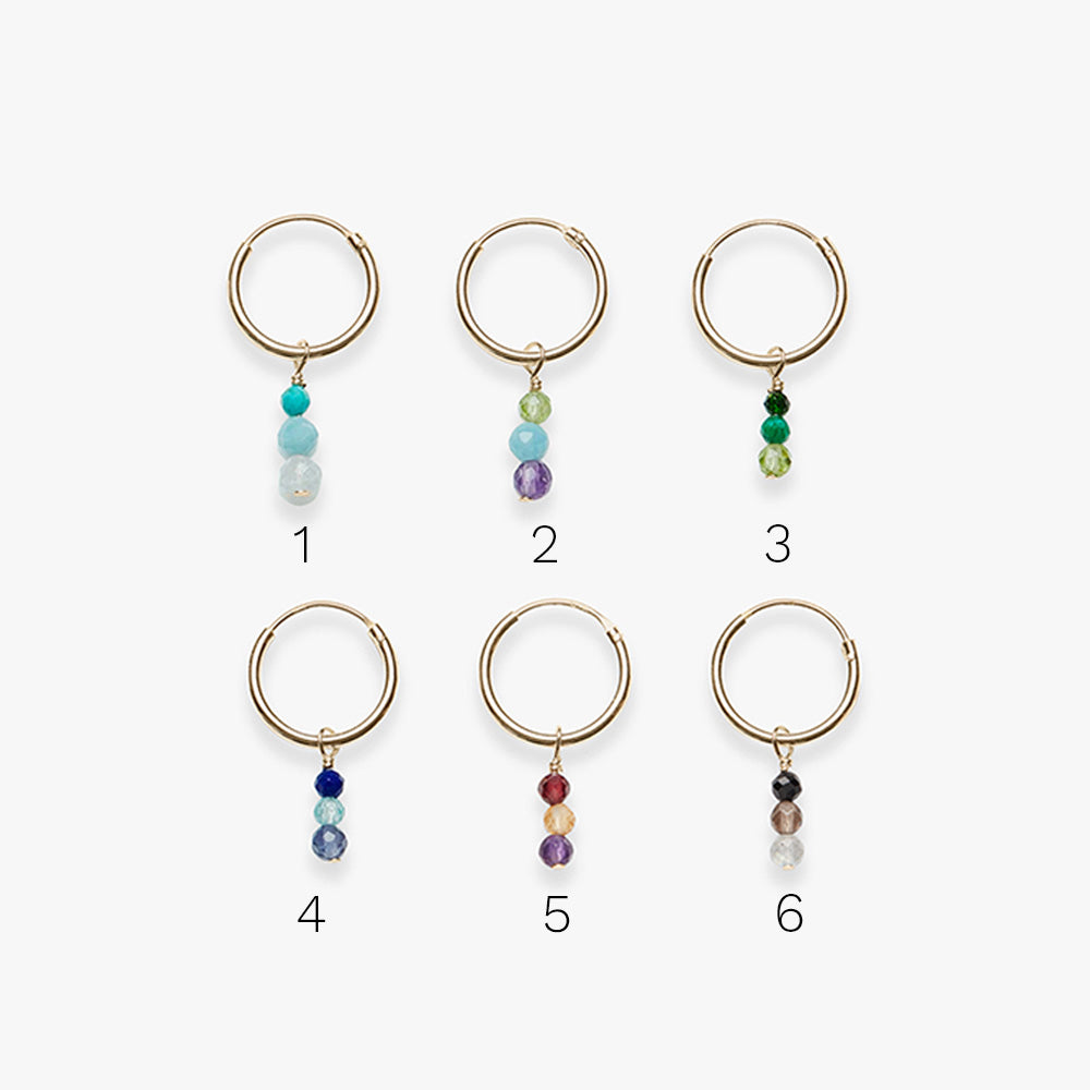 Six gold hoop earrings with colorful beads on a white background