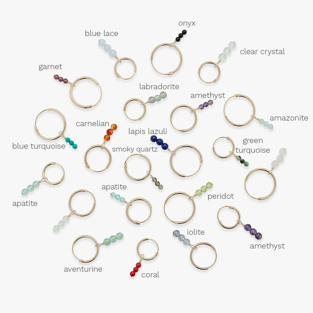 Collection of gold hoop earrings with various gemstones on a white background