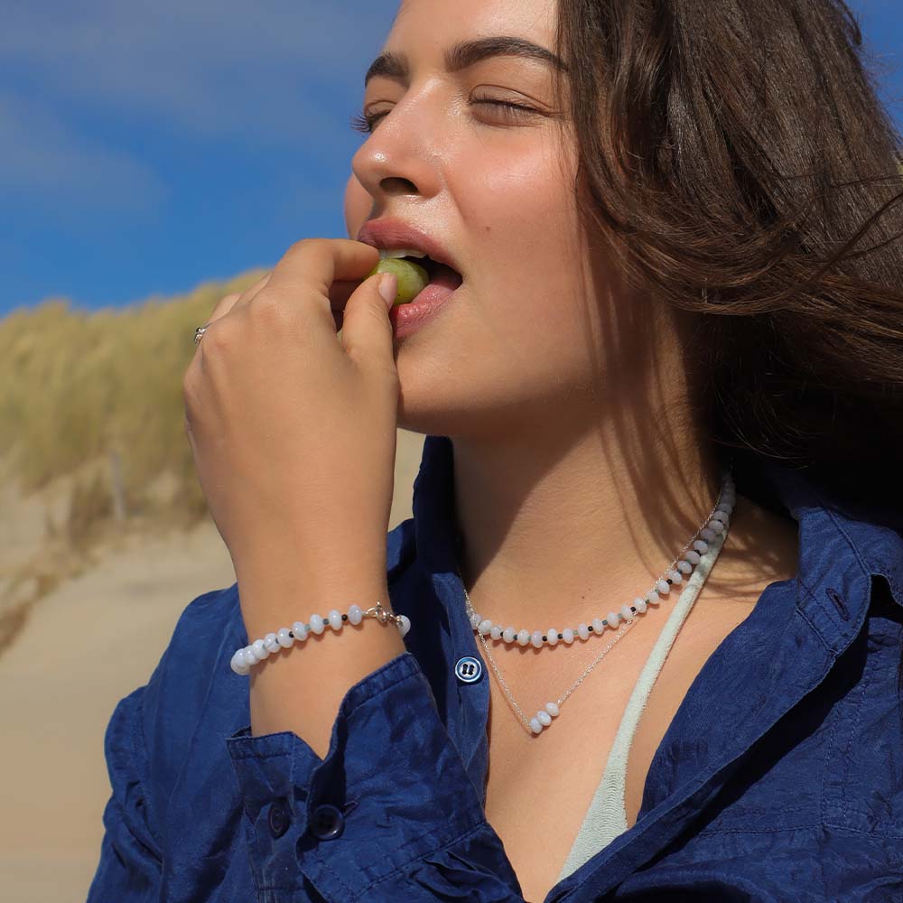 Woman eating a green apple outdoors with a blue sky background