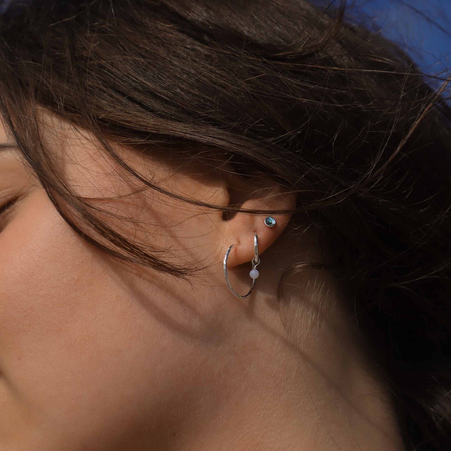 Close-up of a person wearing hoop earrings with a blurred background