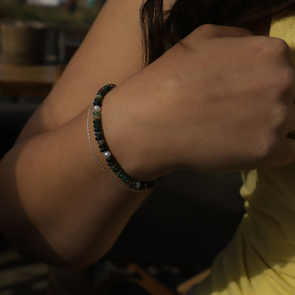 Close-up of a person's wrist wearing two bracelets with a blurred background