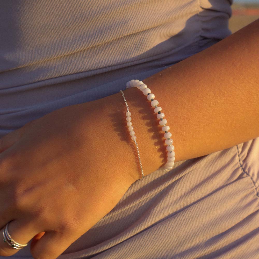 Close-up of a person's arm wearing two bracelets with a neutral background