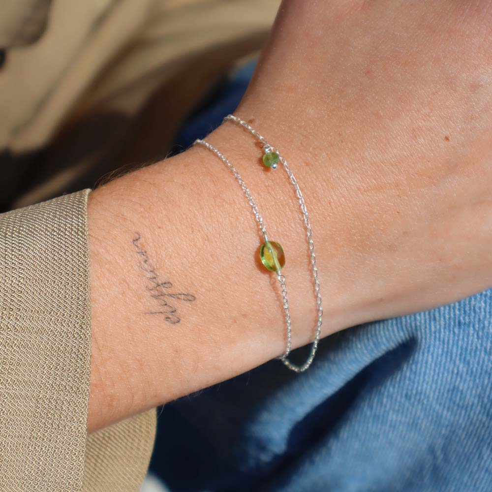 Close-up of a wrist with a silver bracelet featuring a green gemstone.