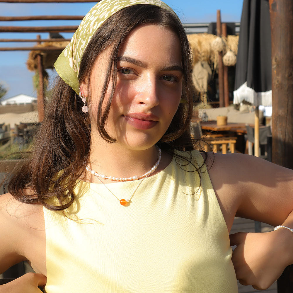 Woman wearing a yellow top and headscarf outdoors