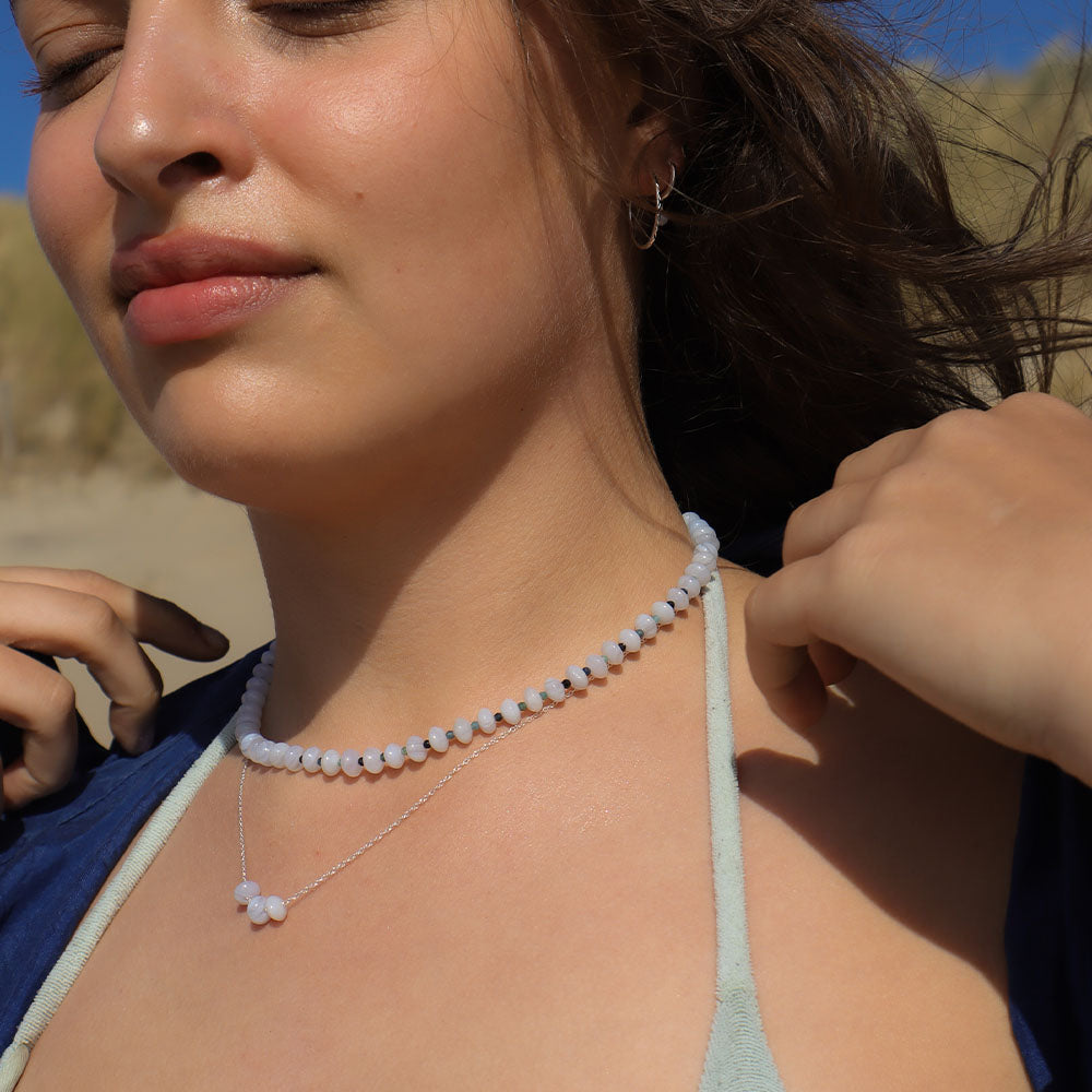 Close-up of a woman wearing a beaded necklace with a blurred natural background