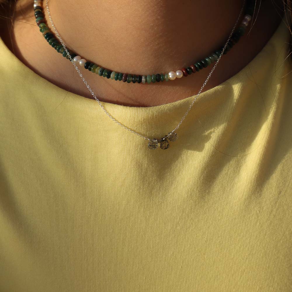 Necklace with a small pendant on a yellow shirt