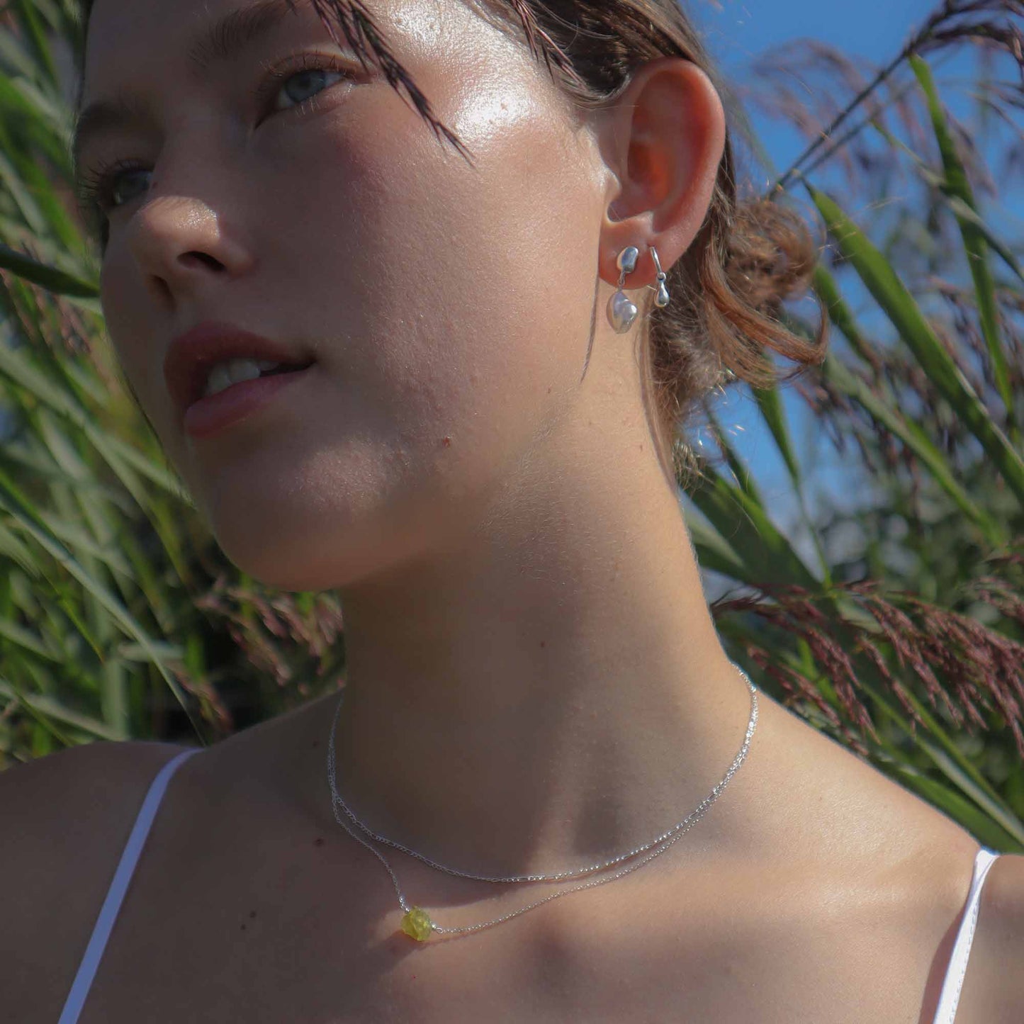 Woman wearing a silver necklace and earrings in a natural setting