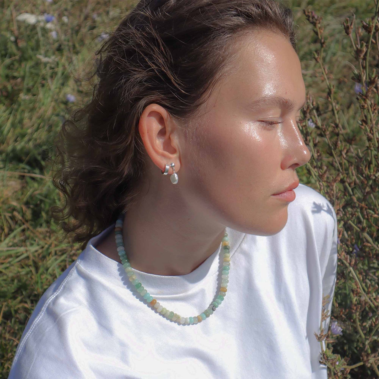 Person wearing a necklace and earrings outdoors