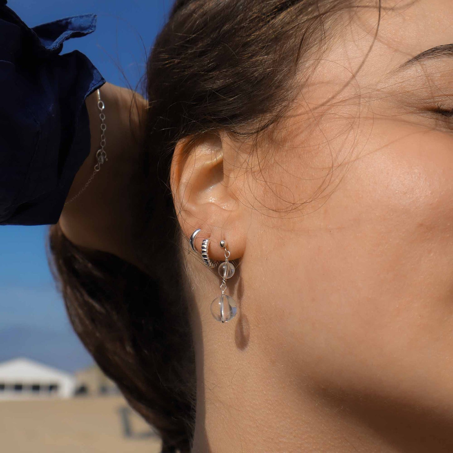 Close-up of a person wearing silver hoop earrings with a blurred background
