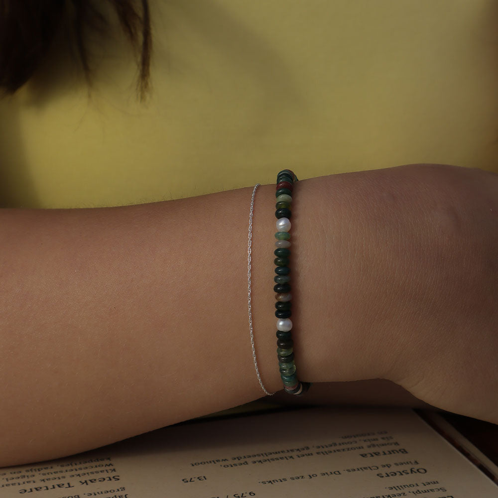Close-up of a wrist wearing a beaded bracelet on a yellow background