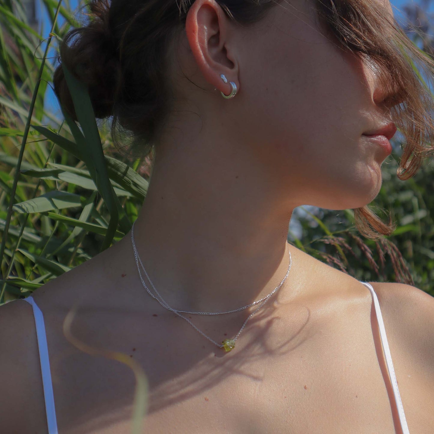 Woman wearing a necklace with a green pendant outdoors