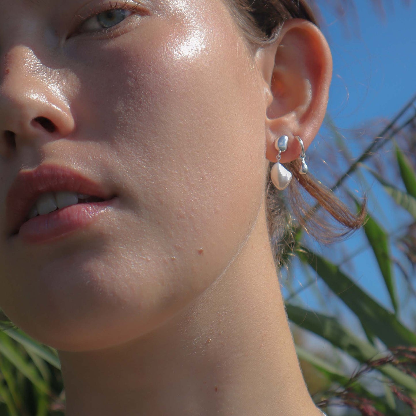 Close-up of a woman's face with a focus on her earrings against a natural background