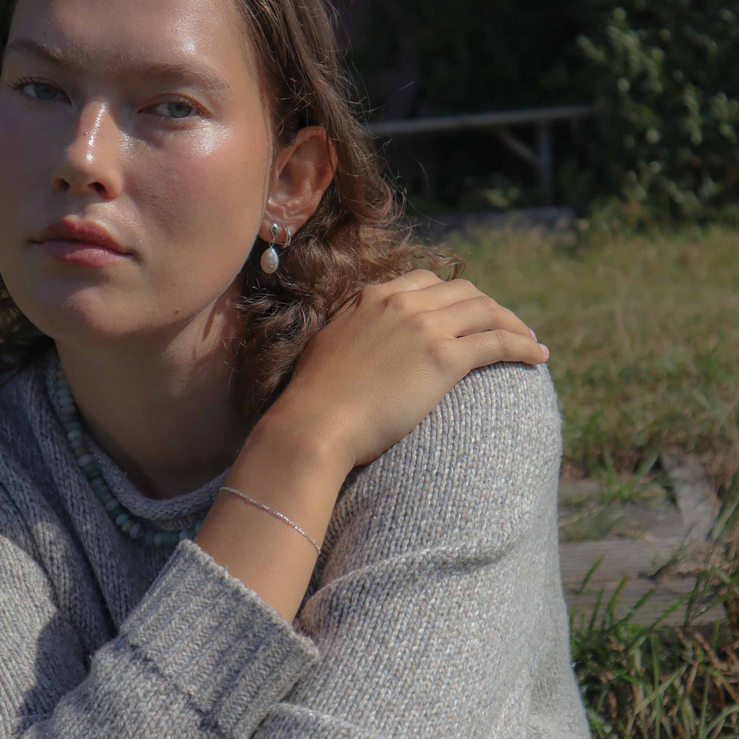 Woman wearing a gray sweater with a blurred natural background