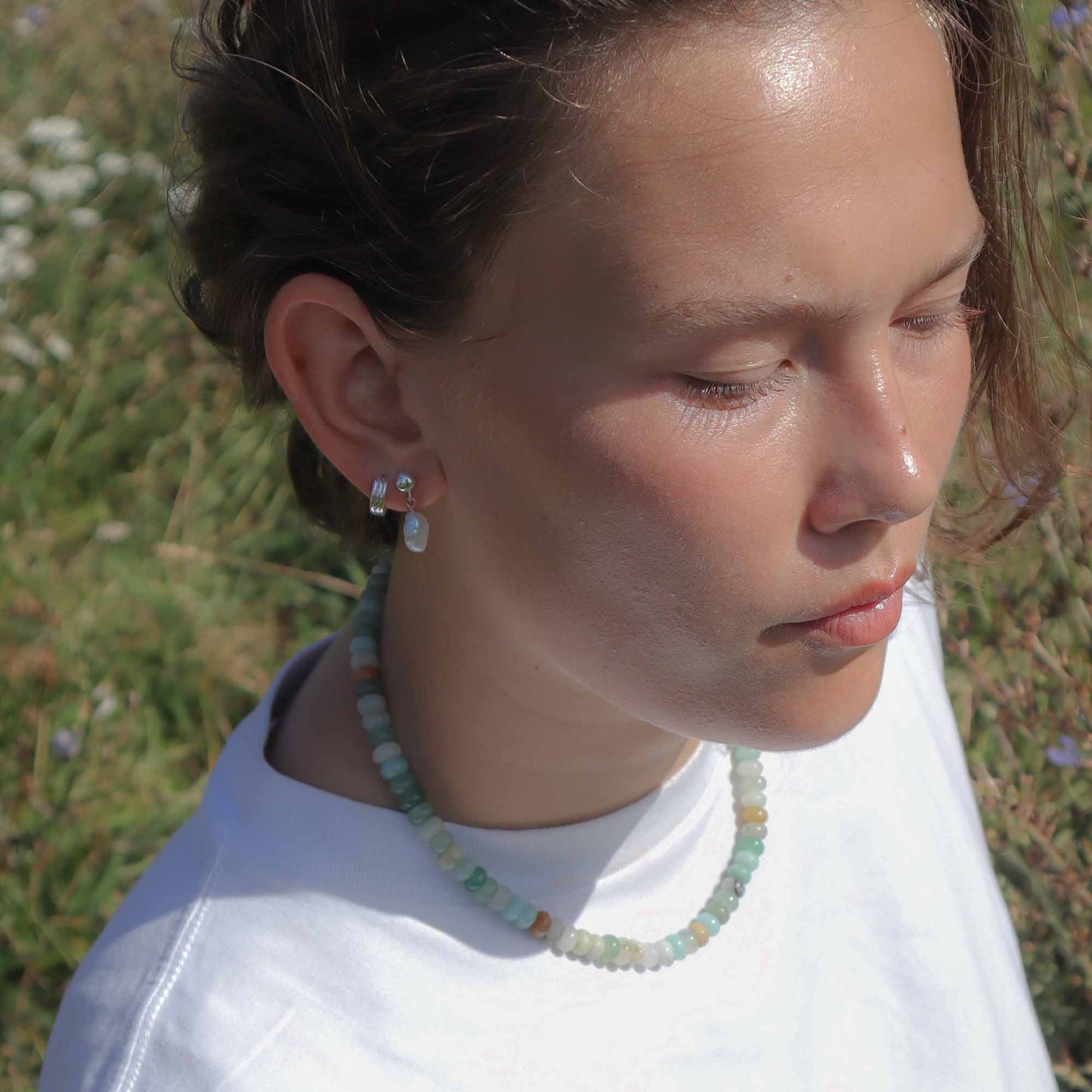 Person wearing a necklace and earrings with a natural background