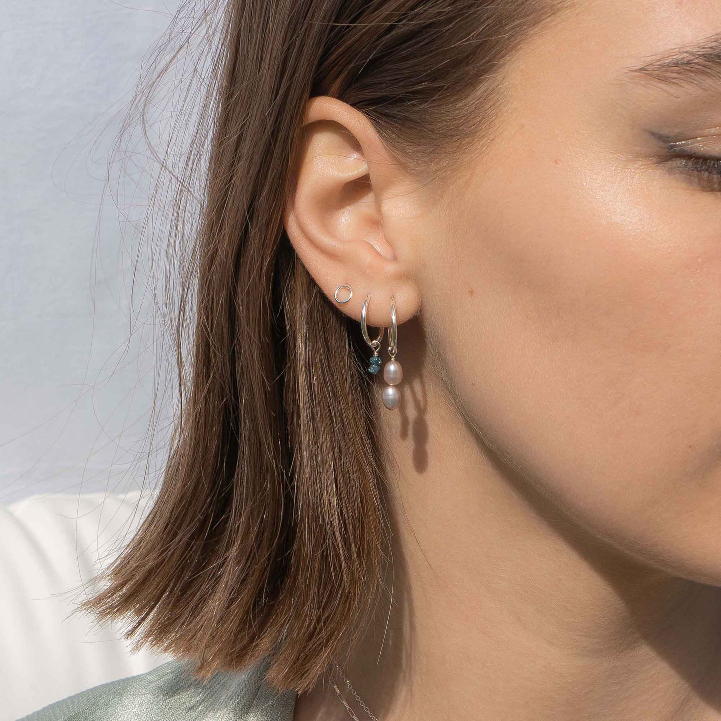 Close-up of a person wearing earrings with a neutral background