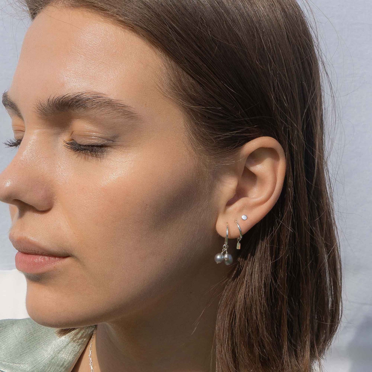 Close-up of a woman wearing silver earrings with a blurred background