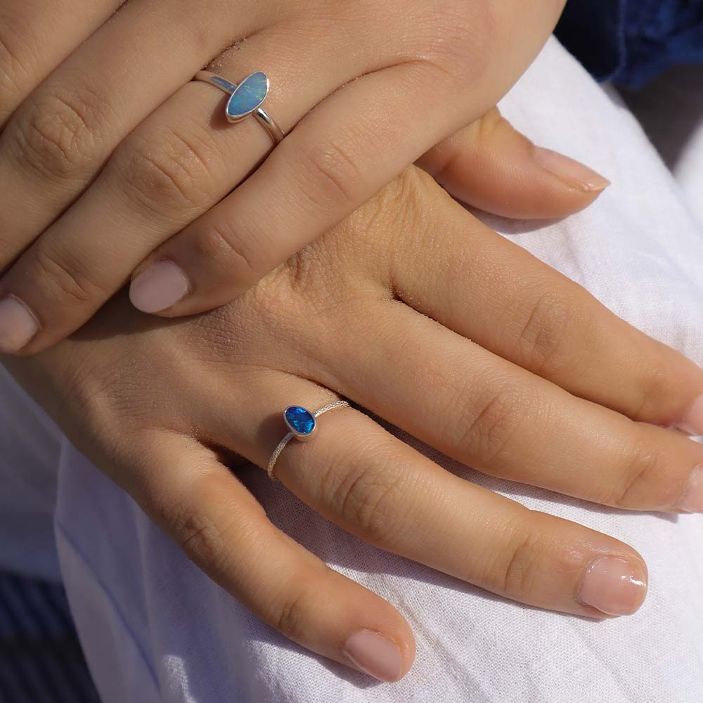 Close-up of hands wearing silver rings with blue stones on a white background