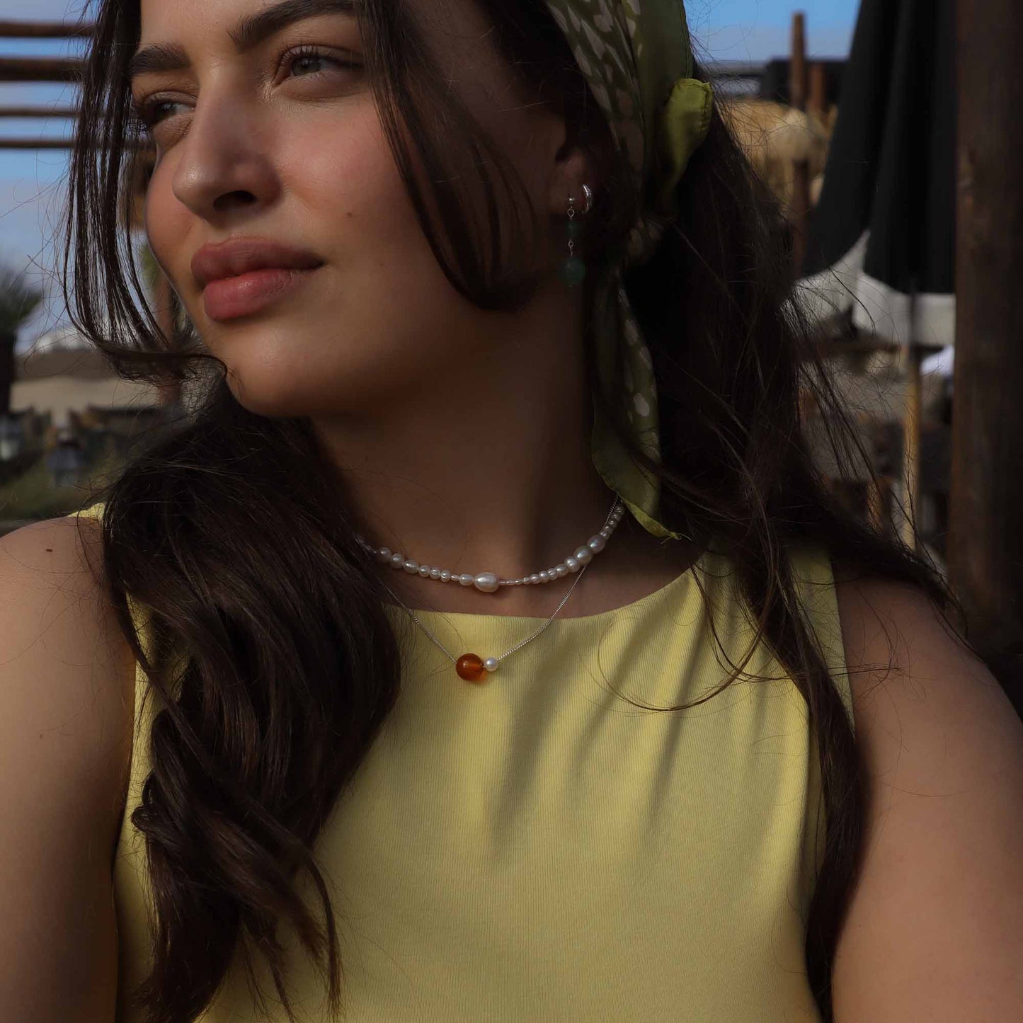 Woman wearing a yellow top and pearl necklace with a blurred background