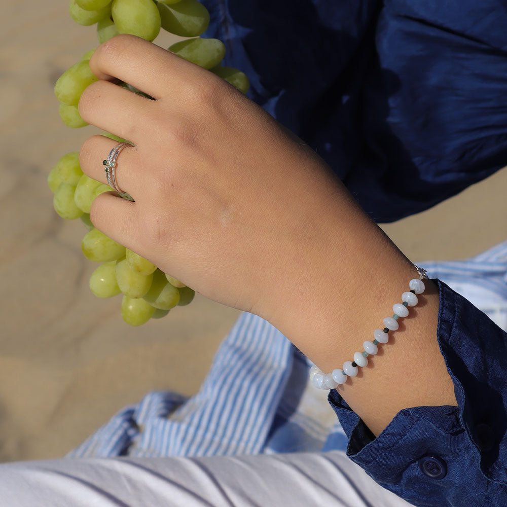 Hand holding green grapes with a bracelet on a blurred background