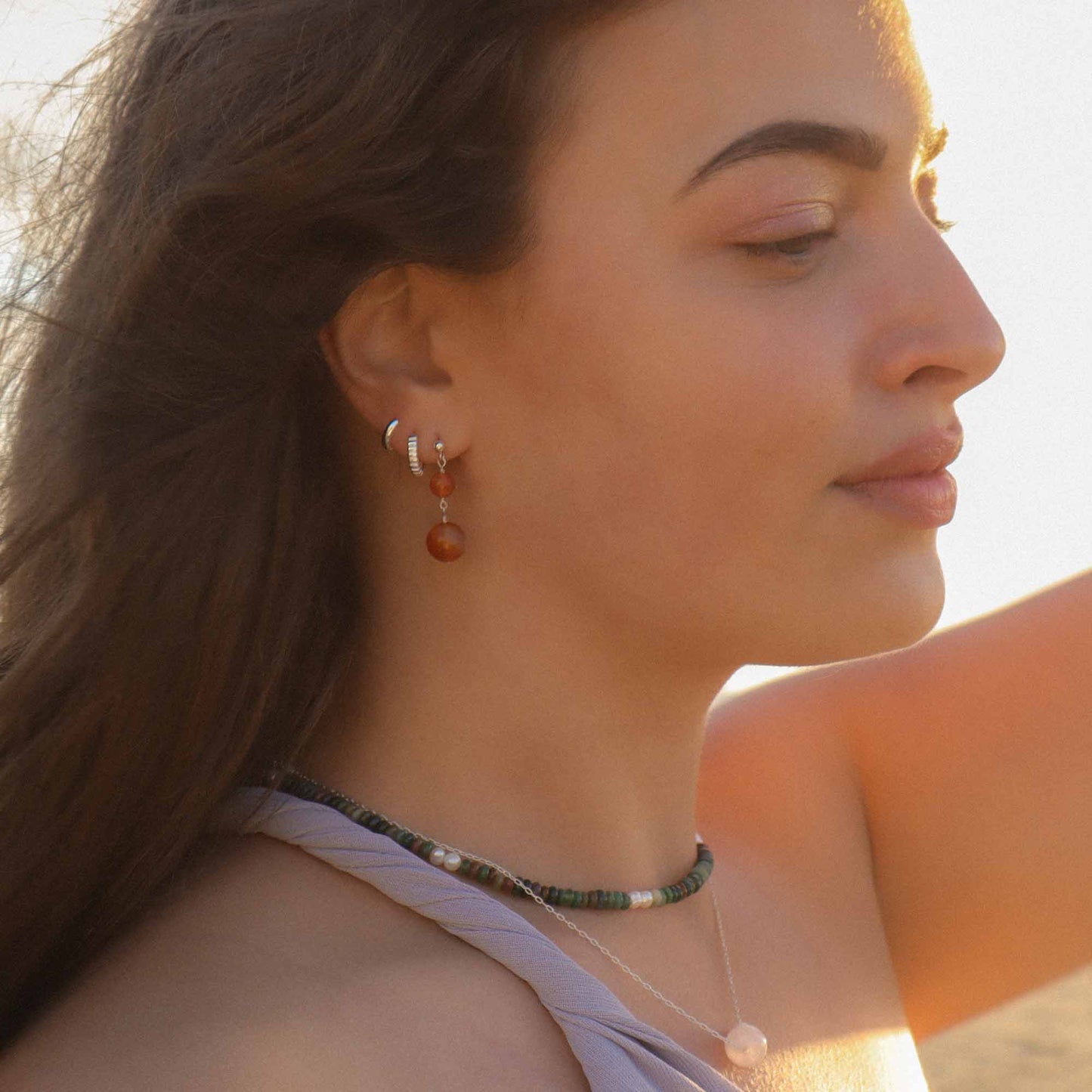 Close-up of a woman wearing earrings and a necklace with a blurred background