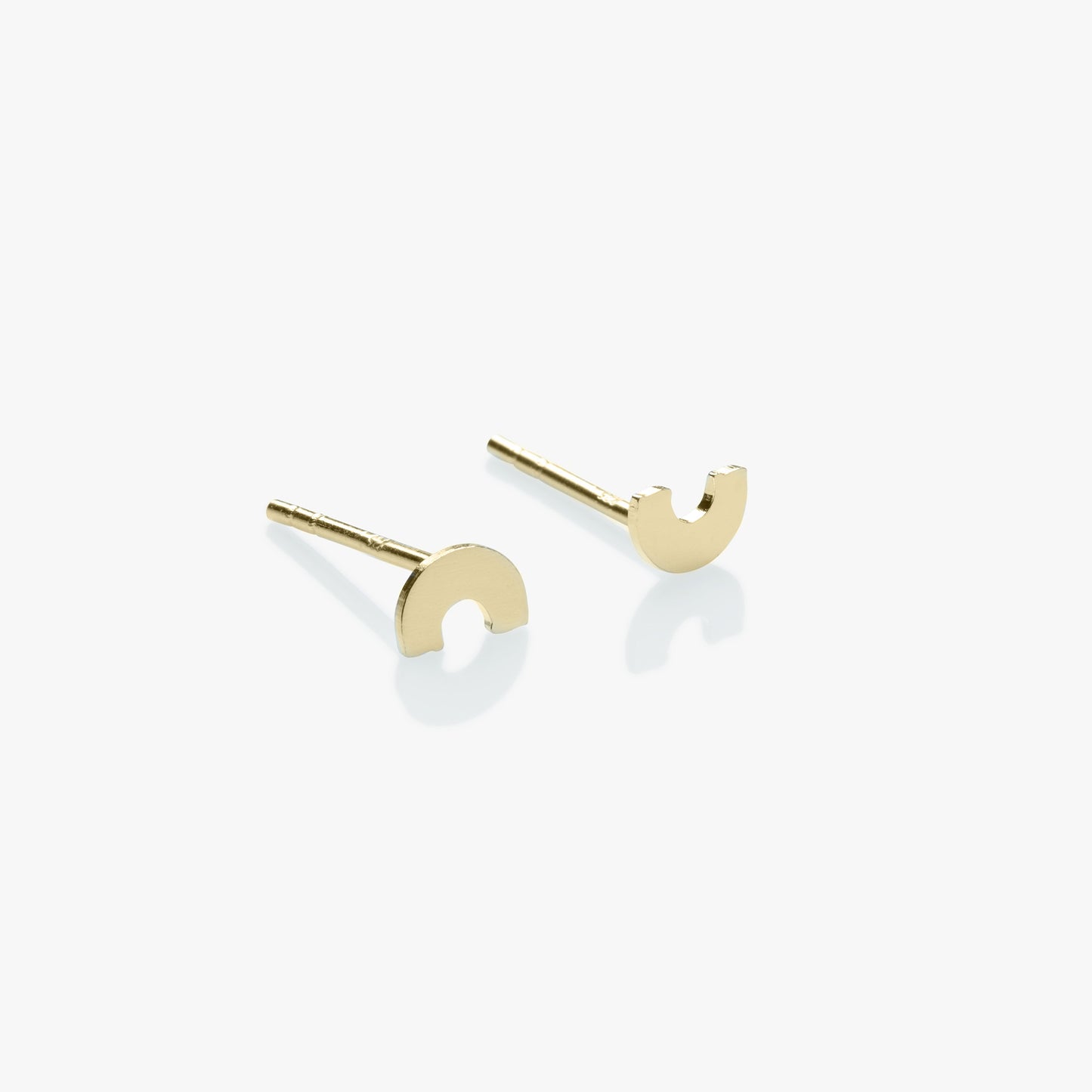 Gold earrings shaped like half-moons on a white background