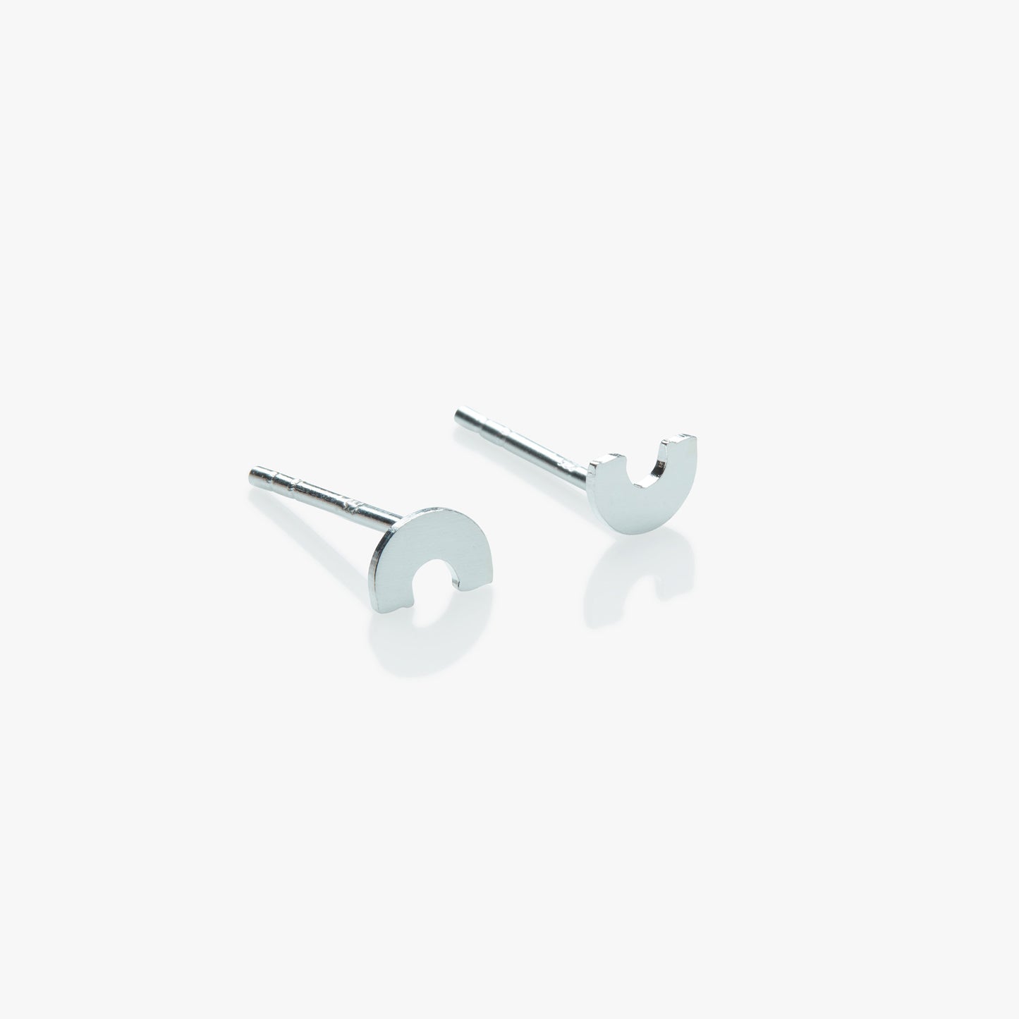 Silver earrings shaped like arches on a white background