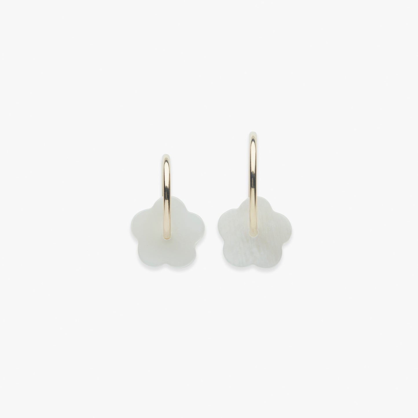 Gold hoop earrings with white flower charms on a white background