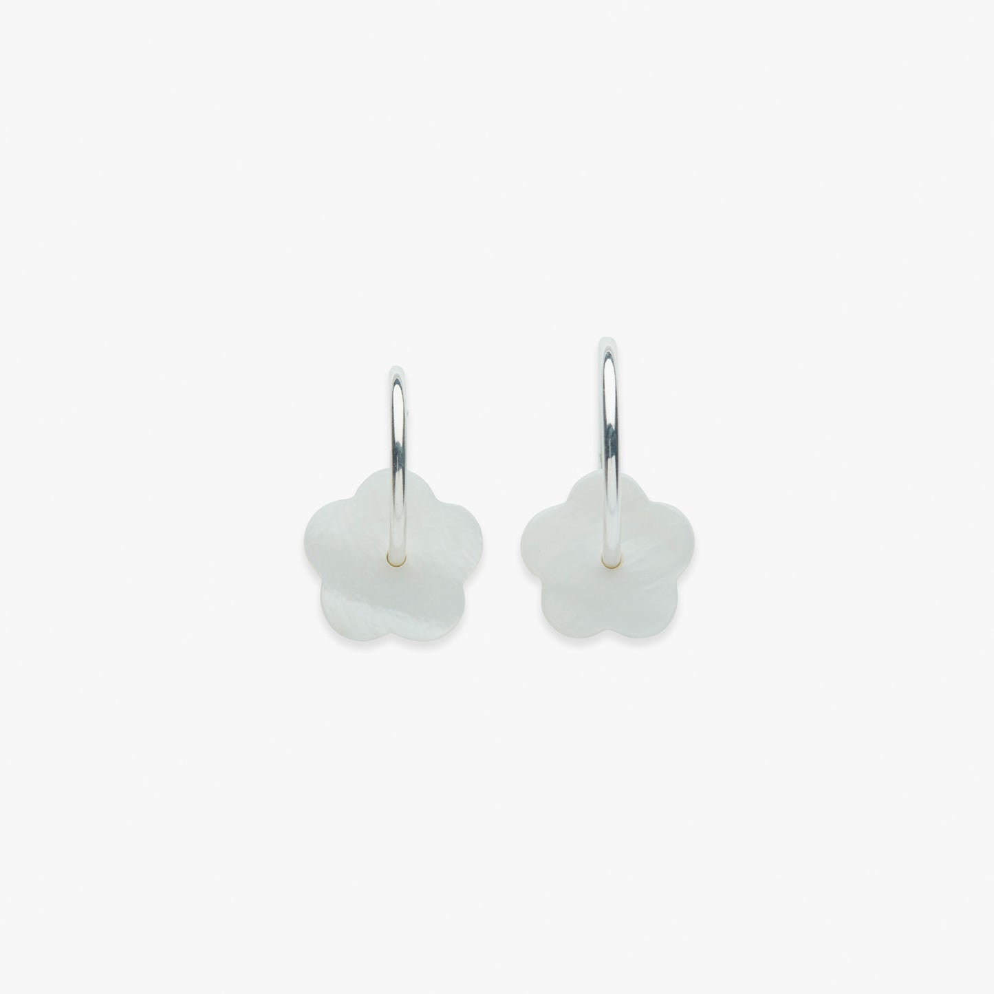 Pair of silver earrings with white floral designs on a light beige background
